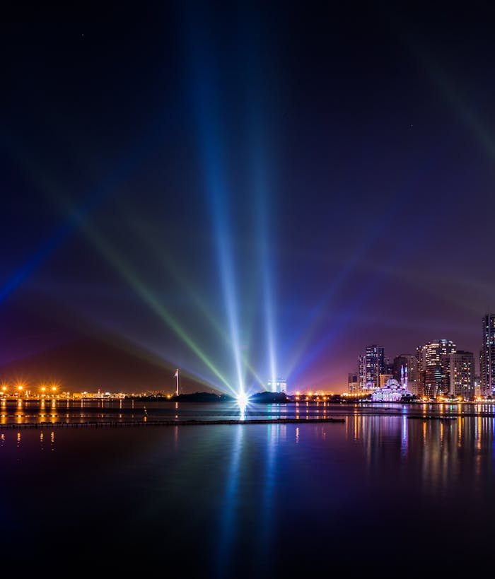 digital-01 Stunning view of Sharjah skyline at night with vibrant lights reflecting on water.