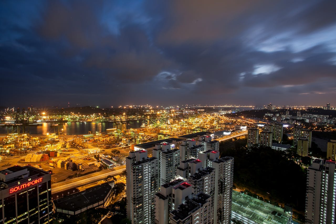 Stunning aerial view of a cityscape at night with skyscrapers and illuminated harbor.